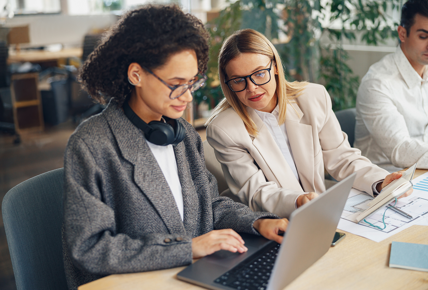 Two women look at a laptop in an office.